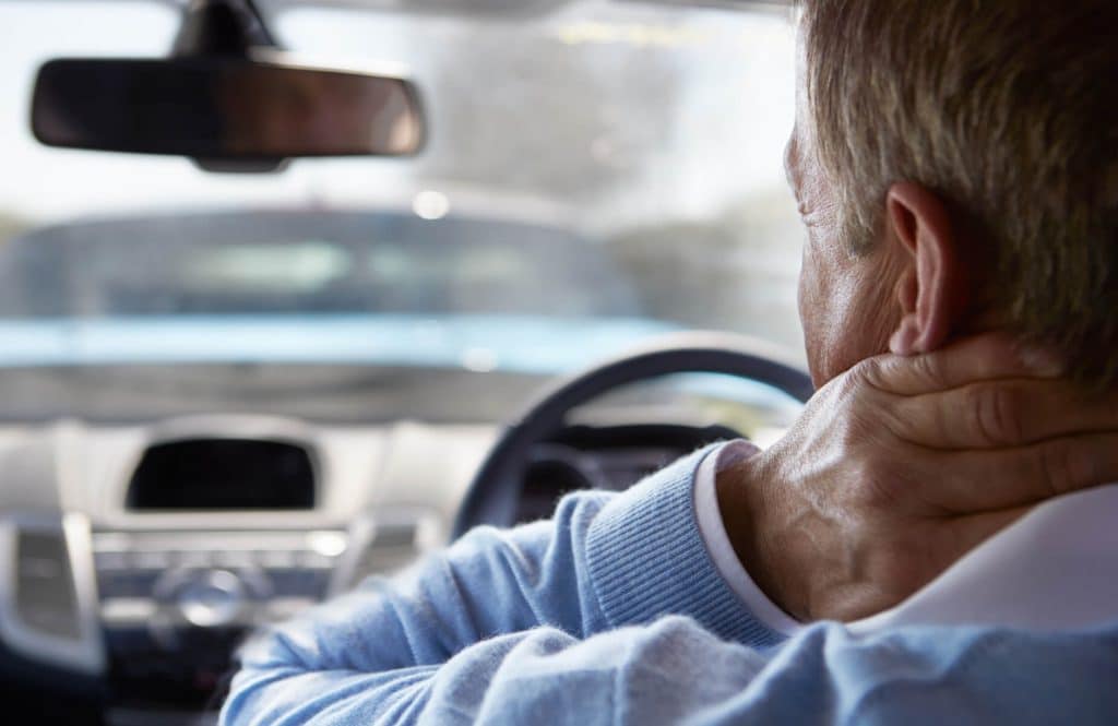 Man inside car holding neck after accident