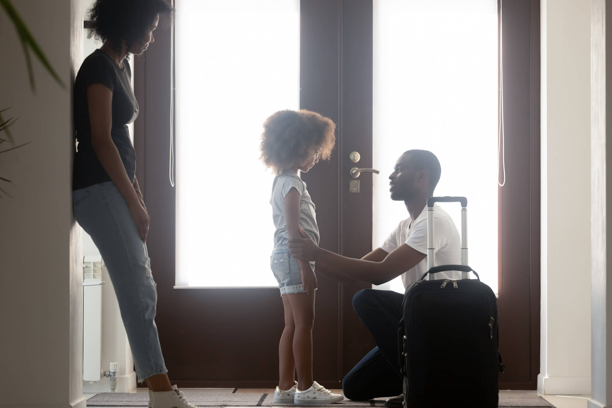 Father kneeling talking to daughter before leaving her with mother